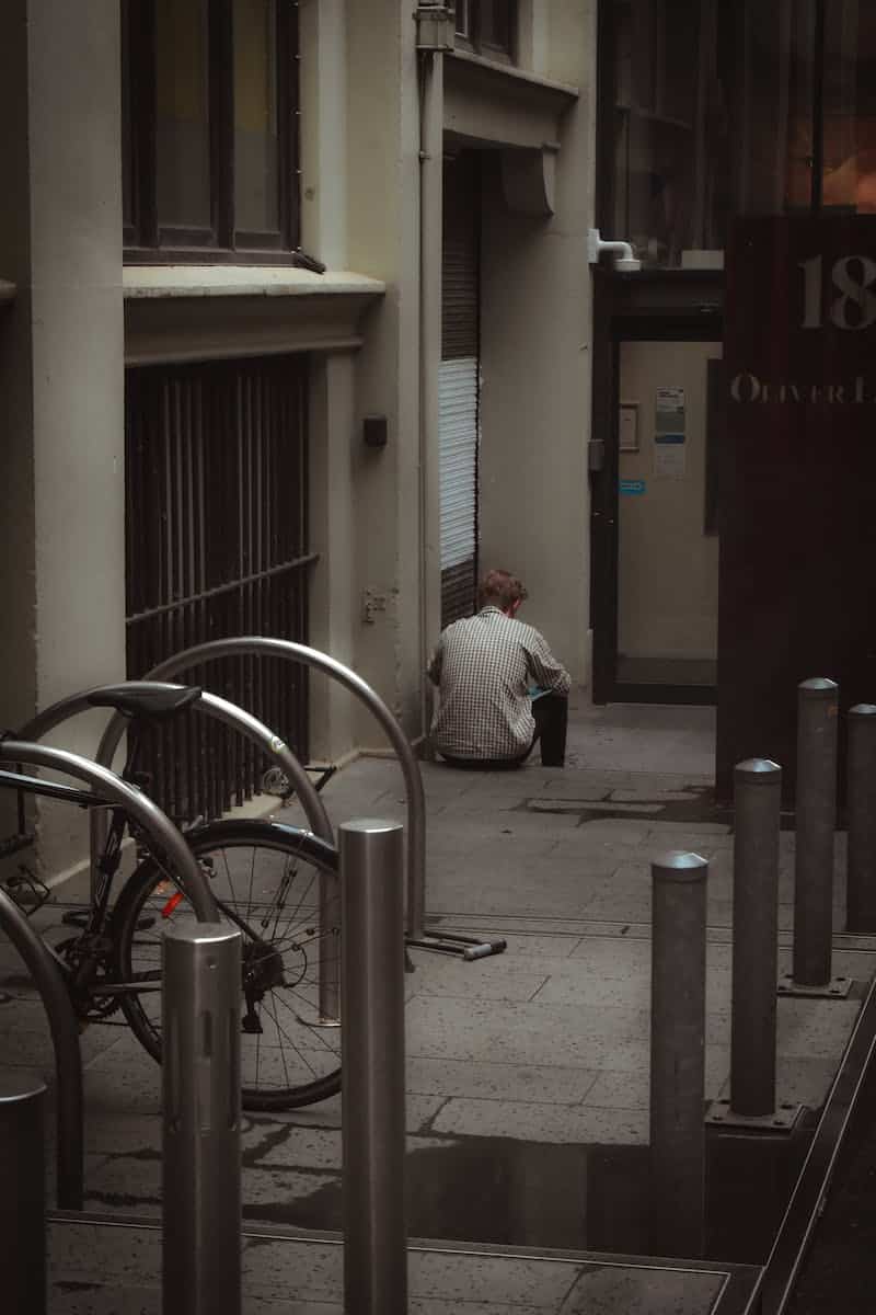 Man Sitting on the Sidewalk